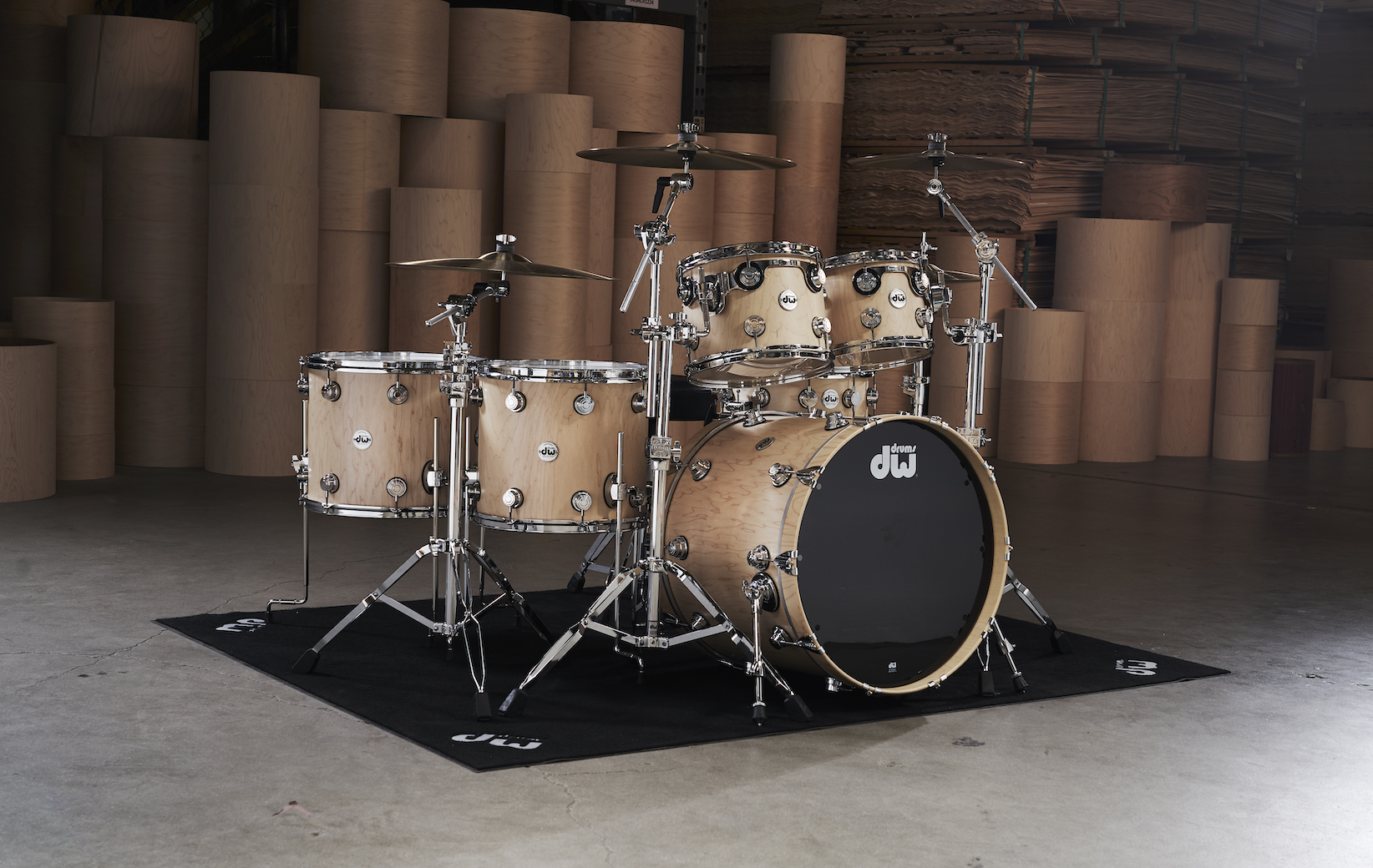 DW maple kit sitting on top of a black DW Drum rug.